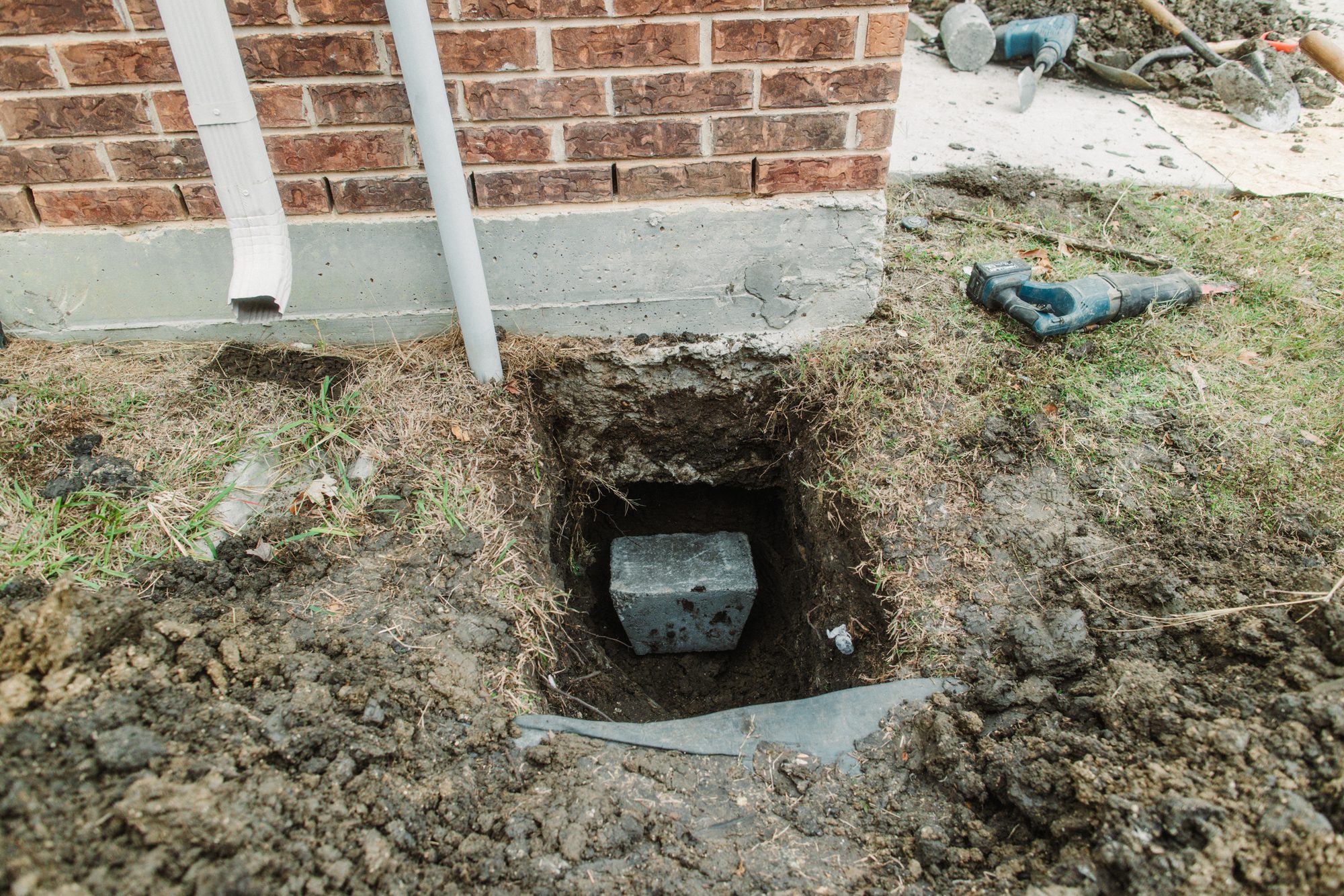 Pier block in hole at downspout, Imperial Foundation Repair job site in North Texas