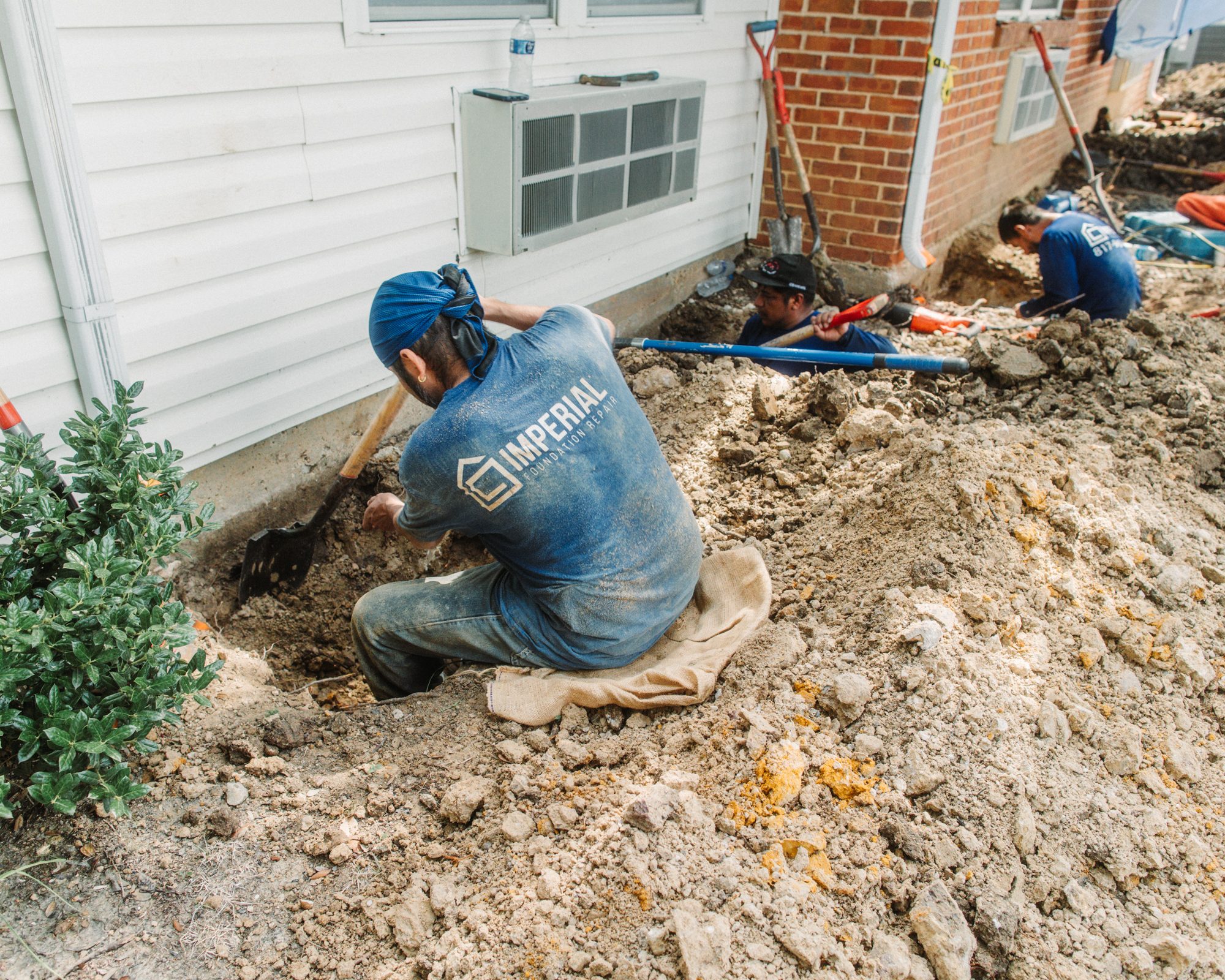Crew digging siding house, Imperial Foundation Repair job site in North Texas